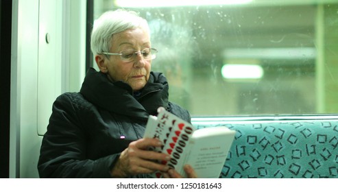 BERLIN, GERMANY, CIRCA JANUARY 2018 - Candid Authentic Real Life Of Older Woman Reading Inside Subway Train