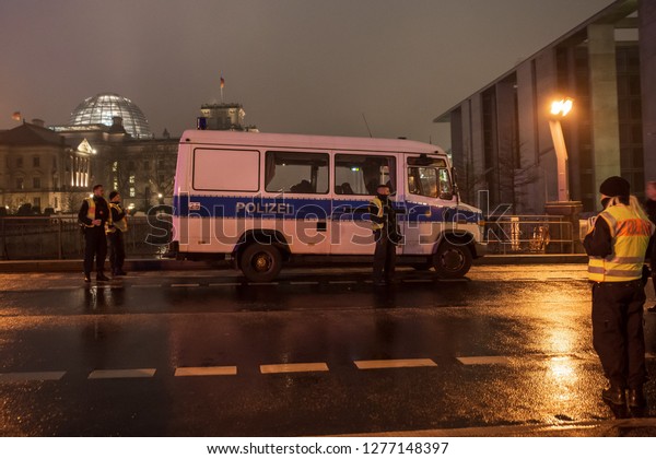 BERLIN, GERMANY - DECEMBER 31, 2018:\
Police on the blocked street during New Year Eve  celebrations. In\
the background building of Bundestag with German\
flags.