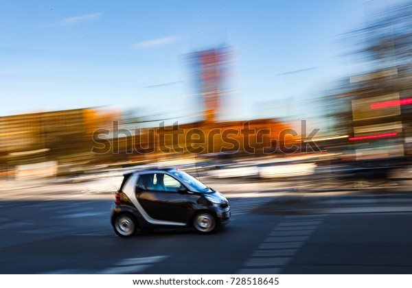 BERLIN, GERMANY - FEBRUARY 21, 2017: Small smart\
electric car on the street with smooth traffic. Future of car\
traffic. Motion\
blurred.