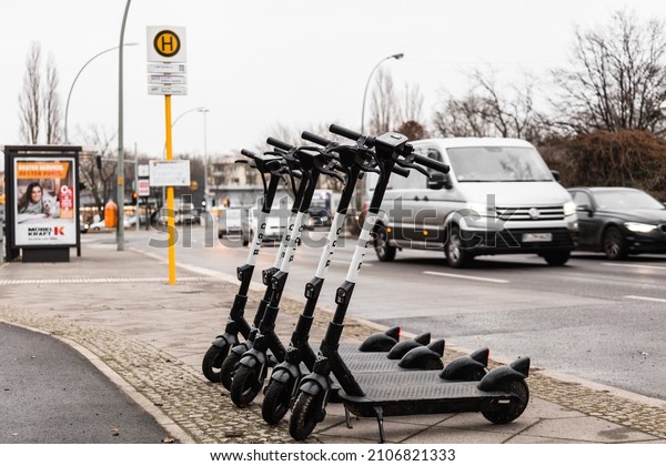 Berlin, Germany - January 13, 2021: E scooters from Bird\
company in front of bus stop and street full of car. This is the\
choice to travel freedomly in the city instead of cars or buses and\
trains. 