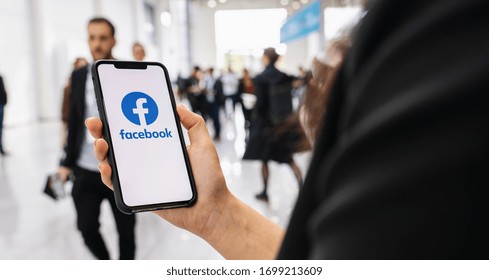 BERLIN, GERMANY JANUARY 2020: Woman hand holding iphone Xs with logo of Facebook application in a pedestrian zone. Facebook is an online social networking service founded February 2004 Mark Zuckerberg