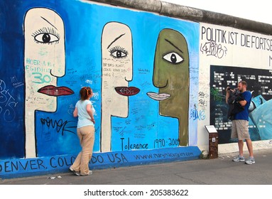 BERLIN, GERMANY - JULY 2, 2014: People taking pictures at the East Side Gallery exhibition, the largest outdoor art gallery in the world, painted on the segment of Berlin wall