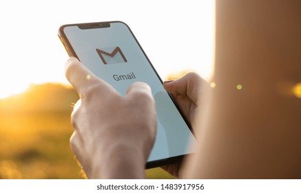 BERLIN, GERMANY JULY 2019: Business woman holding a iPhone with Google Gmail app logo on the display. Gmail is a most popular free Internet e-mail service provided by Google.