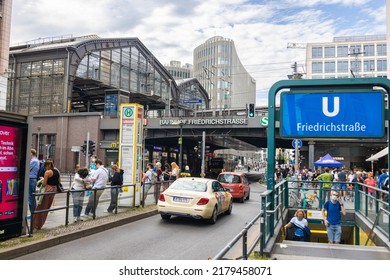 Berlin, Germany - June 29, 2022: Berlin Friedrichstrasse Train Station With The Stairs To The Subway Or Metro Station. Busy Place In East Berlin. People Are Waiting For The Tram. A Taxi Car Passing By