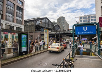 Berlin, Germany - June 29, 2022: Berlin Friedrichstrasse Train Station With The Stairs To The Subway Or Metro Station. Busy Place In East Berlin. People Are Waiting For The Tram. A Taxi Car Passing 