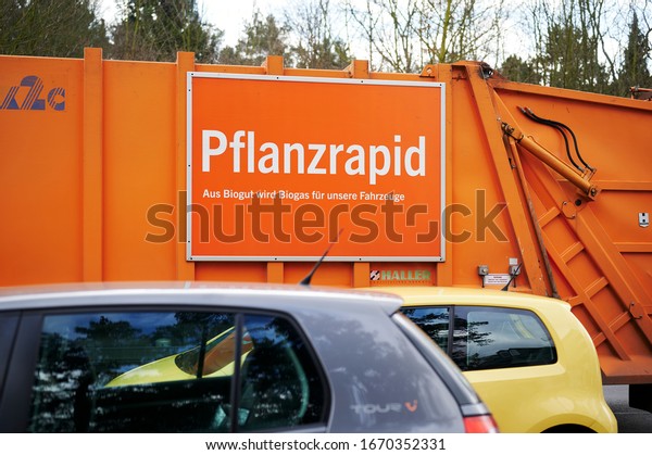 Berlin, Germany - March 11, 2020: Street scene\
with a truck of the Berlin city cleaning. On the side of the truck\
you see a sign that humorously advertises the conversion of organic\
waste into biogas.