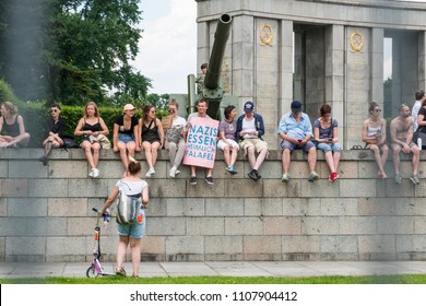 Berlin, Germany - March 2018: Group Of Protesters Sitting On Wall In Berlin One Holding Sign With Slogan 