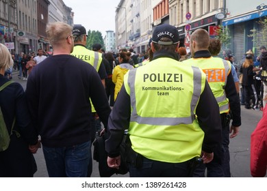 Berlin, Germany - May 1, 2019: Back Turned Policeman Wearing The Yellow Bib Of The Communication Team (German: Kommunikationsteams), Anti-conflict Group Of The German Police