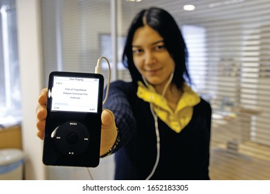 Berlin, Germany- May 13, 2007. Young attractive woman is holding ipod and listening music.