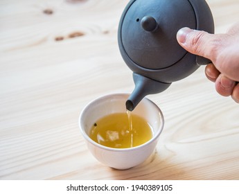 Berlin, Germany - May 19, 2019: A Man Pours Freshly Brewed Japanese Green Tea From A Traditional Tea Pot Into A Cup In A Cafe In Kreuzberg, Berlin. 