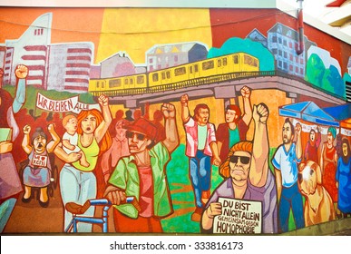 BERLIN, GERMANY - SEPT 1, 2015: Artwork On Wall Graffiti With Crowd Of Immigrants Protesting For Rights On Septemper 1, 2015. Urban Area Of Berlin Comprised 4 Million People, 7th Most Populous In EU