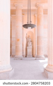 Berlin, Germany: vertical view inside classical sandstone portico of Brandenburg Gate with columns, hanging lamp, and historic stone statue monument.