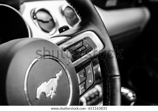 BERLIN - MAY 13, 2017: Control\
buttons for the multimedia system on the steering wheel of the Ford\
Mustang 5.0 V8 Convertible, 2016. Black and white. Exhibition\
\