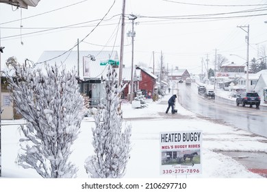 Berlin, Ohio - December 1, 2020: Amish Business Owner Shovels Snow On The Sidewalk On East Main Street.