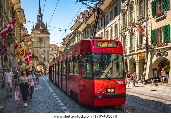 Bern Switzerland , 27 June 2020 :\
Red tram going to Ostring and Kafigturm or prison tower with people\
in Marktgasse street in Bern old town\
Switzerland