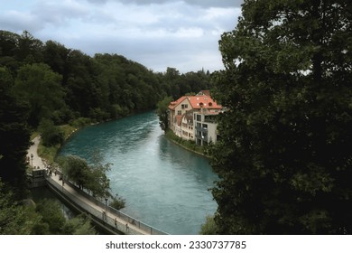 Bern, Switzerland. July 1, 2023. River Aare with a forest on the banks and typical Swiss houses on the opposite side. - Shutterstock ID 2330737785