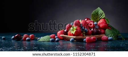 Berries closeup colorful assorted mix of strawberry, blueberry, raspberry and sweet cherry in studio on dark background.