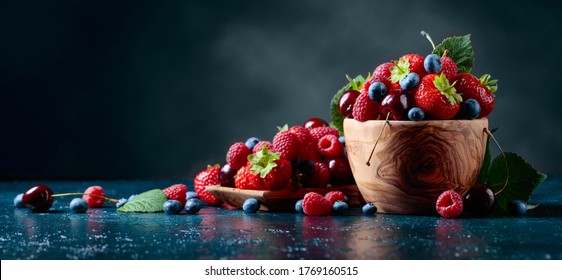 Berries with leaves in wooden dish. Colorful assorted mix of strawberries, blueberries, raspberries and sweet cherries. - Powered by Shutterstock