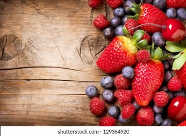Berries on Wooden Background. Summer or Spring Organic Berry over Wood. Strawberries, Raspberries, Blueberry and Cherry. Agriculture, Gardening, Harvest Concept