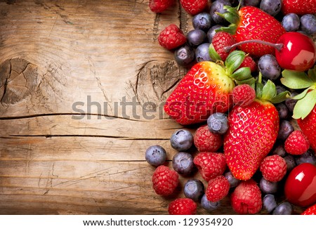 Berries on Wooden Background. Summer or Spring Organic Berry over Wood. Strawberries, Raspberries, Blueberry and Cherry. Agriculture, Gardening, Harvest Concept