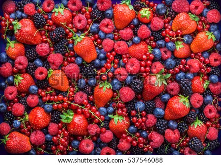 Berries overhead closeup colorful assorted mix of strawberry, blueberry, raspberry, blackberry, red currant in studio on dark background