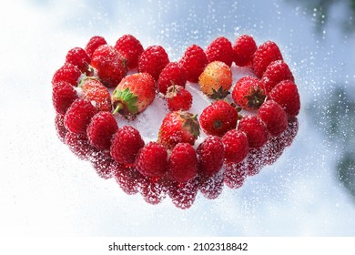 Berries of Raspberries and Strawberries in the shape of a heart on a background of blue sky. Love to celebrate the holiday. Red Raspberry heart. Valentine's day. Healthy eating. Vegan. Love
