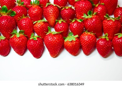 Berries of strawberries of different shapes and sizes lying in even rows on a white background
