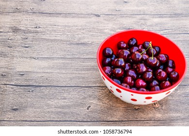 Berries of a sweet cherry on a wooden background in a plastic cup. Ripe red sweet cherry.