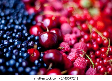Berry assorted - mix of white and red currants, raspberries, strawberries, gooseberries, sweet cherries. Summer harvest - background. Berries of different colors and shapes.