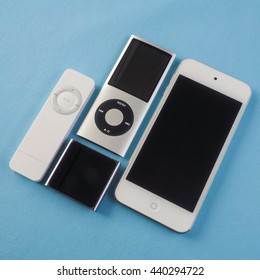 BERRY, AUSTRALIA - June 20 2016 : A group of Apple iPods - iPod Nano 6th generation, iPod Shuffle 1st generation, iPod Touch 5th generation and iPod Nano 4th generation - on a plain blue background.