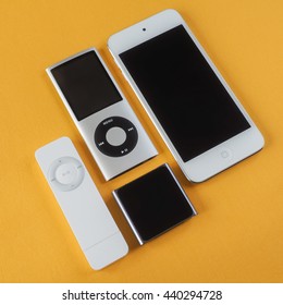 BERRY, AUSTRALIA - June 20 2016 : A group of Apple iPods - iPod Nano 6th generation, iPod Shuffle 1st generation, iPod Touch 5th generation and iPod Nano 4th generation - on a plain yellow background.