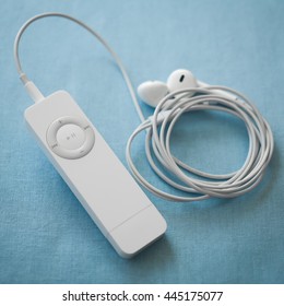 BERRY, AUSTRALIA - June 28 2016 : An Apple IPod Shuffle, First Generation, With Apple Earpods Attached, On A Plain Blue Background.