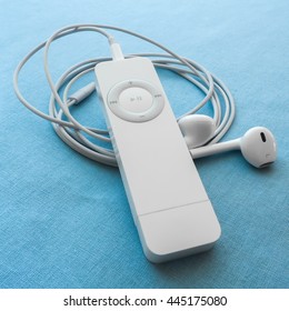 BERRY, AUSTRALIA - June 28 2016 : An Apple IPod Shuffle, First Generation, With Apple Earpods Attached, On A Plain Blue Background.