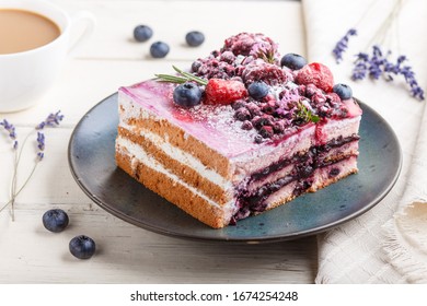 Berry cake with milk cream and blueberry jam on blue ceramic plate with cup of coffee and fresh blueberries on a white wooden background. side view, close up, selective focus.