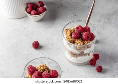 Berry dessert in glass with granola, fresh raspberries, yogurt or cream cheese. Healthy breakfasr concept, vegetarian on gray background. Horizontal - Powered by Shutterstock