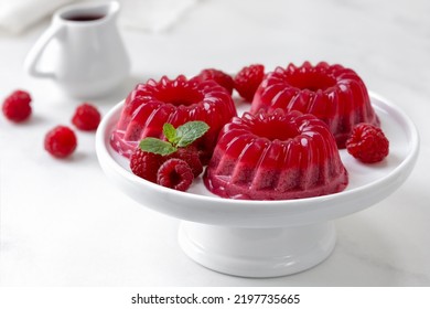 Berry panna cotta or jelly mousse made with pureed raspberries, sugar, cream, gelatine or agar agar. Ready to eat raspberry dessert served on white cake stand with fresh berries. - Powered by Shutterstock