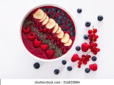 berry smoothie bowl with chia seeds, bananas, blueberries, currant and raspberries on white background