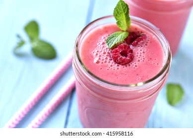 Berry smoothie in a mason jar on a blue wooden table.