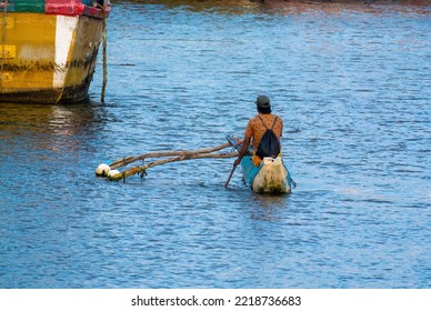 Beruwala, Sri Lanka 09-12-2022
A Man With A Backpack Traditional Boat Called Oruwa Paddling Toward The Trawler Boats Parked Area In The Baruwala Fishing Harbor Bay.