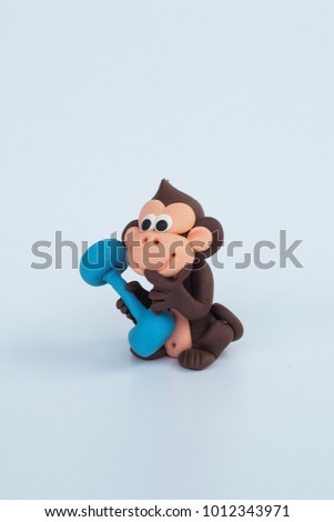 Beside of brown monkey clay plasticine is lifting dumbbell with naughty face on white background concept healthy , exercise , diet