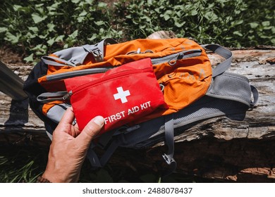 Beside the orange backpack, a person has a first aid kit for emergencies. Personal protective gear is crucial for safe travel and outdoor activities, ensuring a secure and enjoyable experience