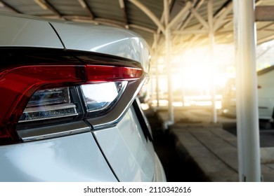 Beside Tail Lights Of White Car In Parking Area. Parked In A Covered Garage With Blurred Of Other Cars.