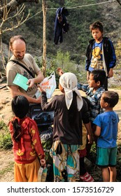Besisahar, Nepal - March 18, 2014: European tourists give notebooks, pens and school supplies to poor Nepalese children. Volunteer assistance to poor children in the Himalayas, Nepal.