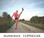 Bespectacled Blonde Teen Majorette Girl Twirling Baton Outdoors in Workout Clothing