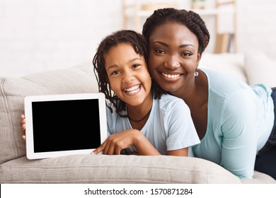 Best App. Black Mom And Daughter Smiling, Girl Holding Digital Tablet. Mockup, Empty Space