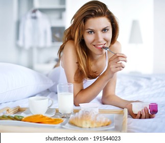 The Best Breakfast In Bed / Woman Eating Healthy Yogurt In Bed While Happy And Smiling 