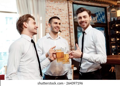 Best Company For The Friday Night Party. Four Friends Businessmen Drink Beer And Rejoice Together At The Bar