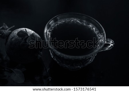 Best detoxify drink on a black glossy surface in a glass cup. Beetroot tea in a transparent glass cup on a black surface with a raw beet and some mint leaves. Horizontal shot with blurred background.