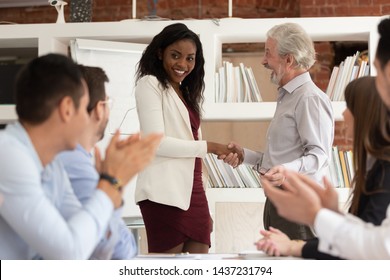 Best Employee Concept, Proud Tolerant Old Senior Manager Boss Handshaking Promoting Rewarding Happy African Black Young Woman Office Worker, Team Applauding, Recognition Acknowledgement At Work