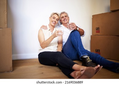 The Best Empty Nest Money Can Buy. Shot Of A Mature Couple Toasting With Water After A Successful Day Moving House.